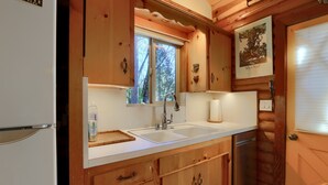 Una cocina con armarios de madera, un lavamanos doble y una ventana.