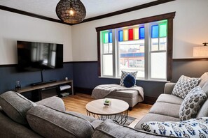 A living room with a flat-screen TV, a sofa, a coffee table, and a window with colorful panes. - Magnificent Ancestral dwelling (Scotstown)