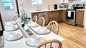 A modern kitchen with wooden cabinets, a stainless steel stove, and a dining area set for six with white plates and bowls.