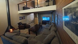 A spacious living room with a high ceiling, a fireplace, a large flat-screen TV, and a comfortable seating area. - Chilling in the Boat! Location, Comfort & Style (Steamboat Springs)