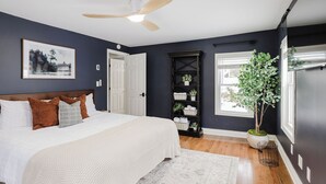 Un dormitorio con cama, ventilador de techo, ventana y planta.