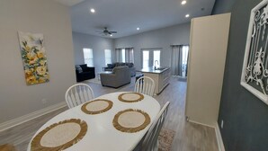 A spacious living area with a dining table, sofas, and a kitchen.