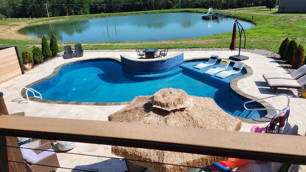 A backyard with a swimming pool, a hot tub, and a small pond.