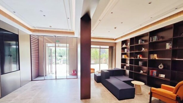 A modern lobby with a seating area, a bookshelf, and a glass door leading outside. - Yisitin Hotel (Taiyuan North Zhonghuan Street Zoo) (Taiyuan)
