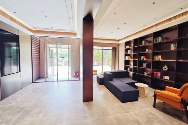 A modern lobby with a seating area, a bookshelf, and a glass door leading outside. - Yisitin Hotel (Taiyuan North Zhonghuan Street Zoo) (Taiyuan)