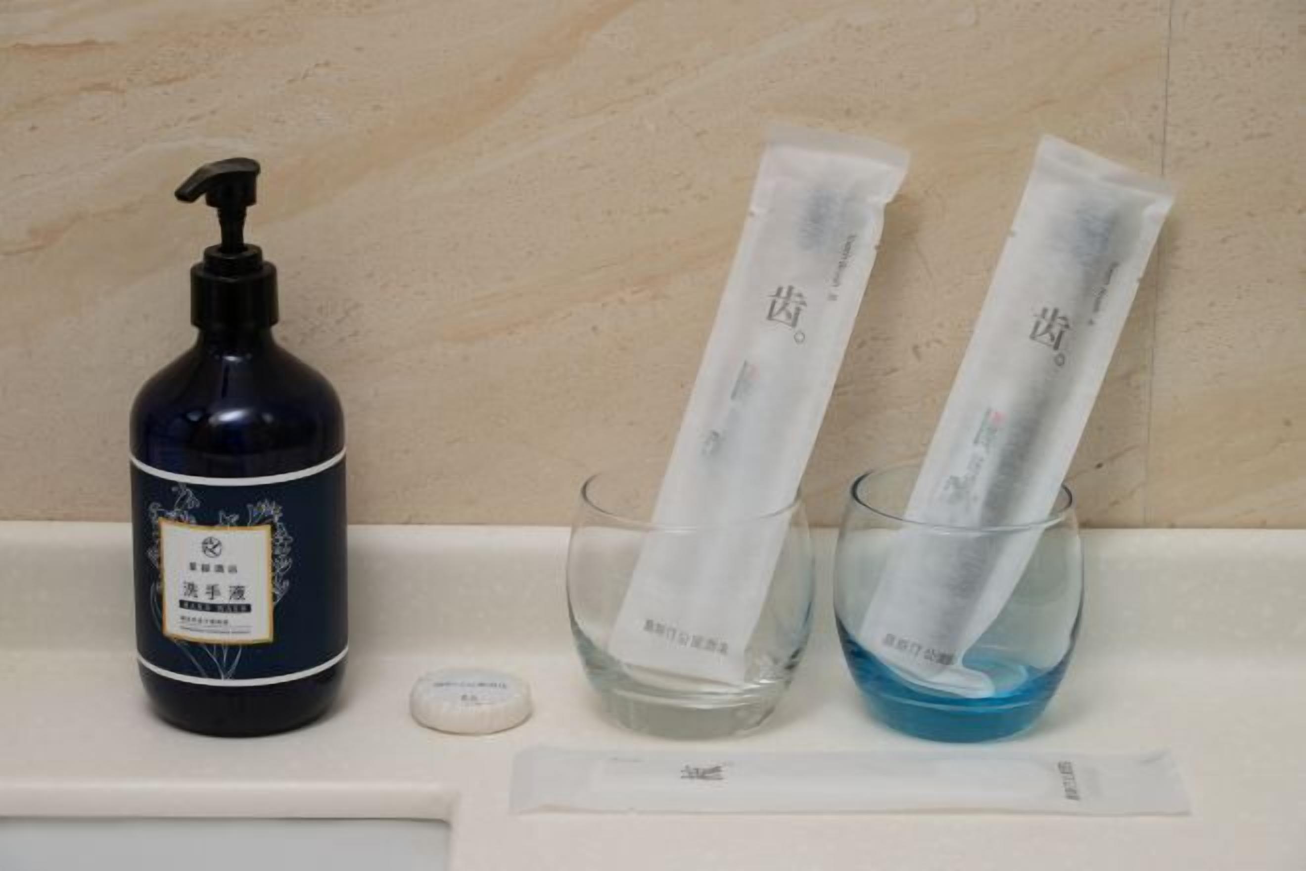 A bathroom with a dark bottle, two glass containers with white strips, and a small bottle on a counter.
