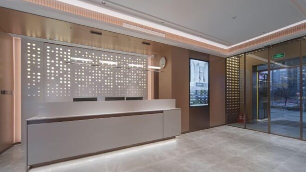 A modern reception area with a sleek reception desk, a patterned wall, and a glass door leading outside. - Yisitin Hotel (Taiyuan North Zhonghuan Street Zoo) (Taiyuan)