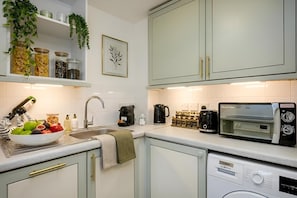 A kitchen with a sink, a coffee maker, a toaster, and a dishwasher.