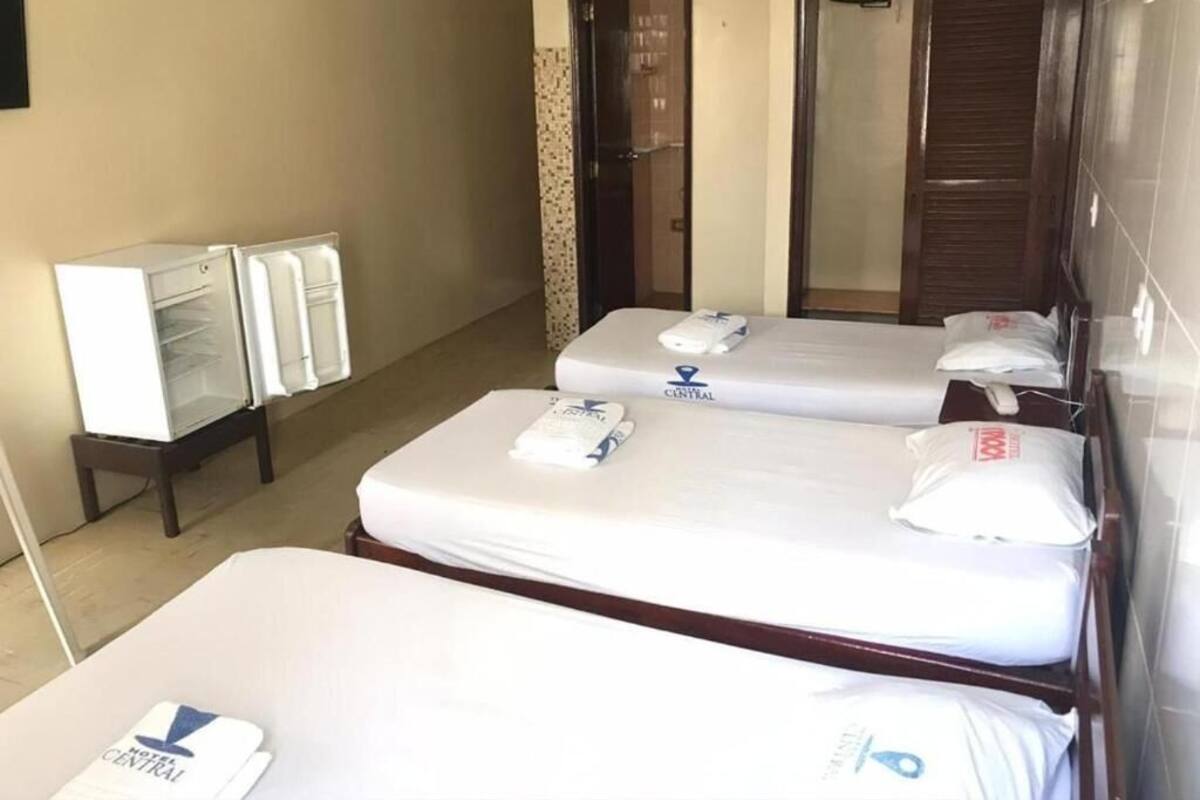A hotel room with two beds, a refrigerator, and a wardrobe.