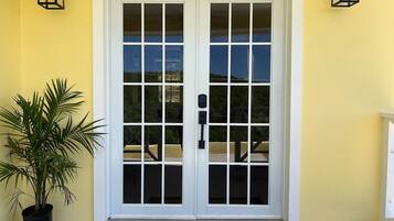 A double door with a glass panel, a welcome mat, and a potted plant.
