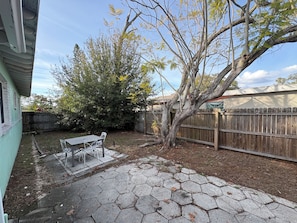 A backyard with a hexagonal stone patio, a wooden fence, and a tree. - Gulfport Getaway — Artsy Retreat 10 Min to Beach (Gulfport)