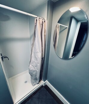 Ein Badezimmer mit Dusche, Toilette und Spiegel.