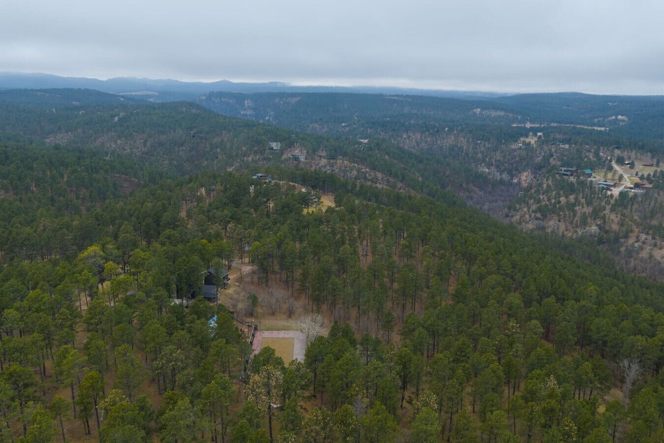 A forested mountain area with a small clearing and a few buildings.