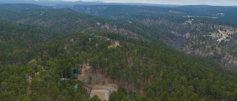A forested mountain area with a small clearing and a few buildings.