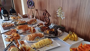 A buffet table with various food items including pastries, bread, and fruits. - Villa Giglio Pousada Atibaia  (Atibaia)