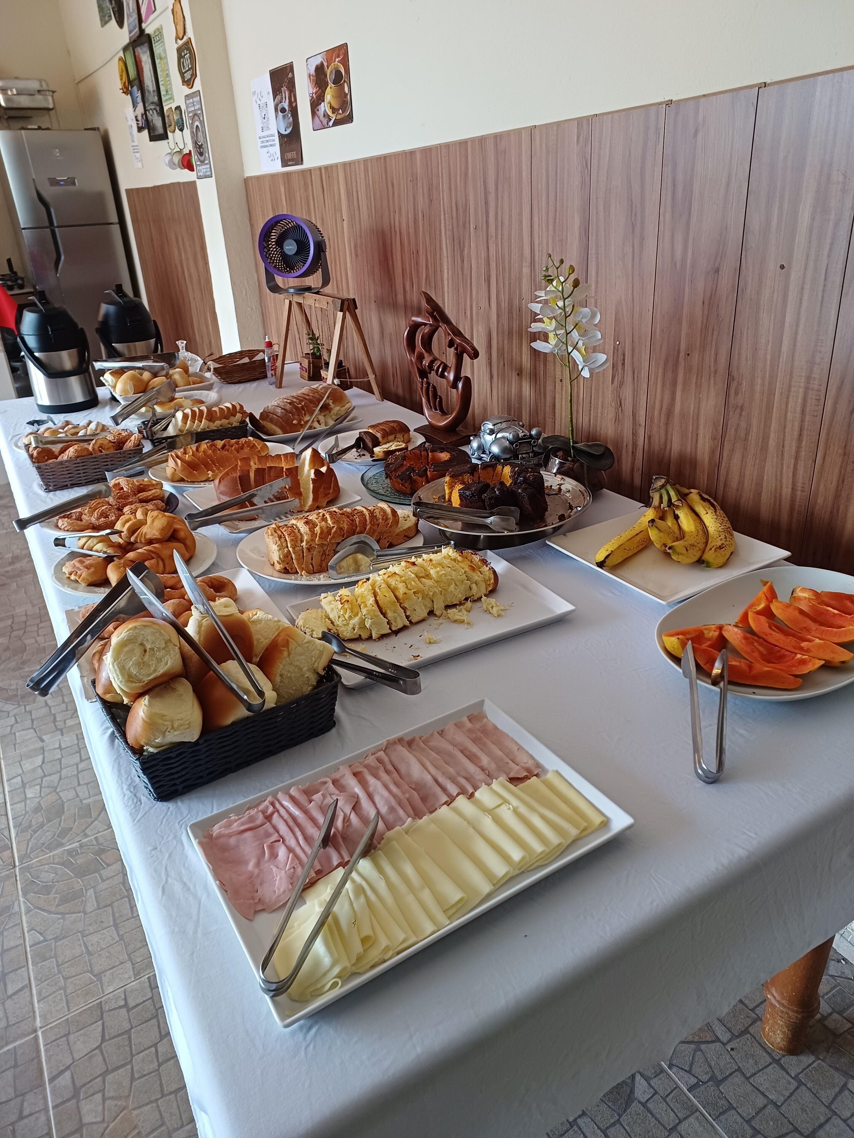 A buffet table with various food items including bread, pastries, and fruits.