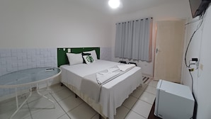A hotel room with a bed, a small table, a television, and a ceiling fan. - Villa Giglio Pousada Atibaia  (Atibaia)