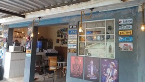 A small, rustic eatery with a blue exterior and a metal roof. It features a counter with a microwave, a wooden table, and chairs. The walls are adorned with various posters and license plates. - Villa Giglio Pousada Atibaia  (Atibaia)