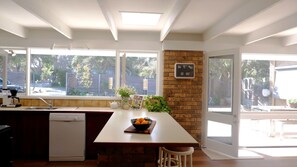 A kitchen with a large window, a brick wall, and a clock. - Moonah Haven in Old Lonnie (POINT LONSDALE)