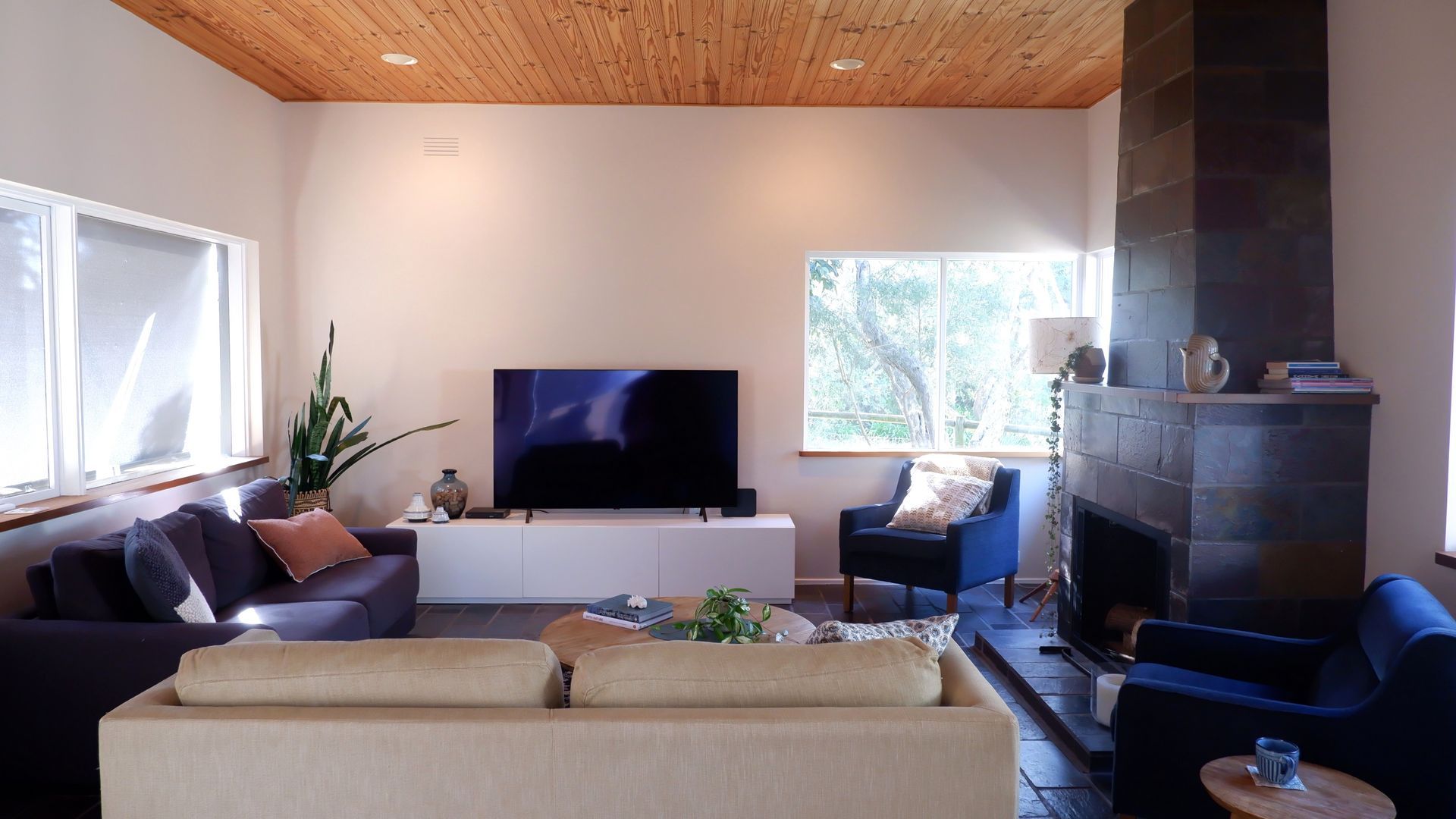 A modern living room with a flat-screen TV, a fireplace, and a large window.