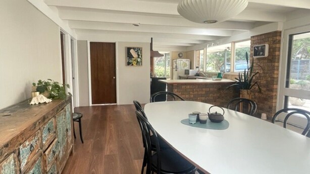 Un espace repas comprenant une longue table, des chaises, un buffet en bois et une porte.