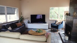 A living room with a flat-screen TV, a sofa, a coffee table, and a fireplace. - Moonah Haven in Old Lonnie (POINT LONSDALE)