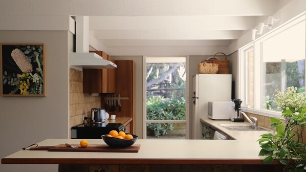 A kitchen with a wooden countertop, a bowl of fruit, and a view of the outdoors.