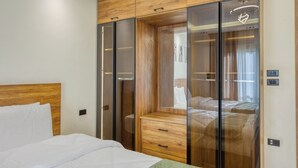 Une chambre à coucher avec une tête de lit en bois, un lit avec une literie blanche, une commode en bois et un dressing avec des portes coulissantes.