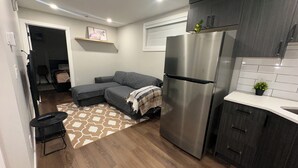 Una cocina compacta con refrigerador incorporado, muebles oscuros y una pequeña encimera.