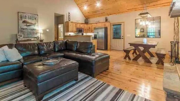 A cozy living room with a sectional sofa, a dining table, and a kitchen in the background. - Comfortable Cabin in Hiawassee across from Lake&Fairgrounds (Hiawassee)
