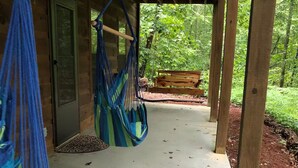 A covered porch with a concrete floor, wooden beams, and a bench in the background. - Comfortable Cabin in Hiawassee across from Lake&Fairgrounds (Hiawassee)