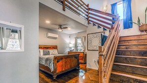 A bedroom with a wooden bed, a staircase, and a large window. - Mountain Top House with a View - Elk House (Ruidoso)