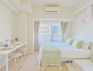 Une chambre à coucher avec un lit, un bureau avec des chaises et une fenêtre avec des rideaux.
