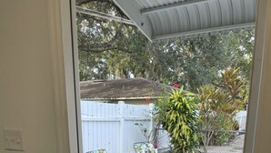 Eine Terrasse mit Gartenmöbeln, einem weißen Zaun und verschiedenen Pflanzen.