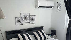 Ein ordentlich eingerichtetes Schlafzimmer mit Bett, Nachttisch, Lampe und Wandbildern.
