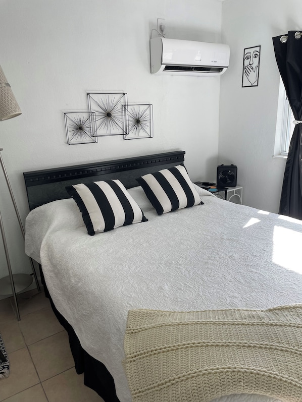 A neatly arranged bedroom with a bed, a bedside table, a lamp, and wall art.