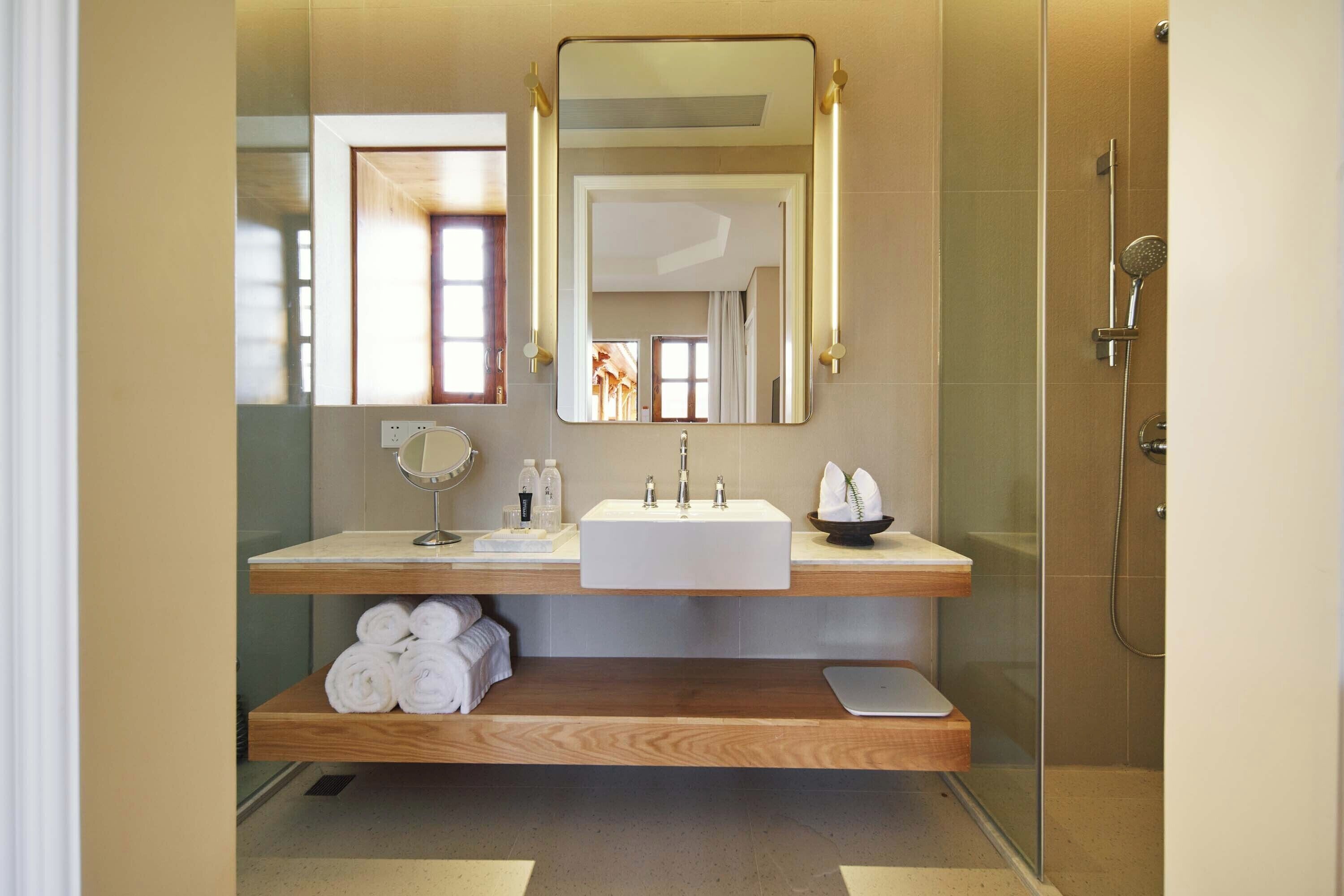 Une salle de bain moderne avec un grand miroir, un lavabo et une douche.