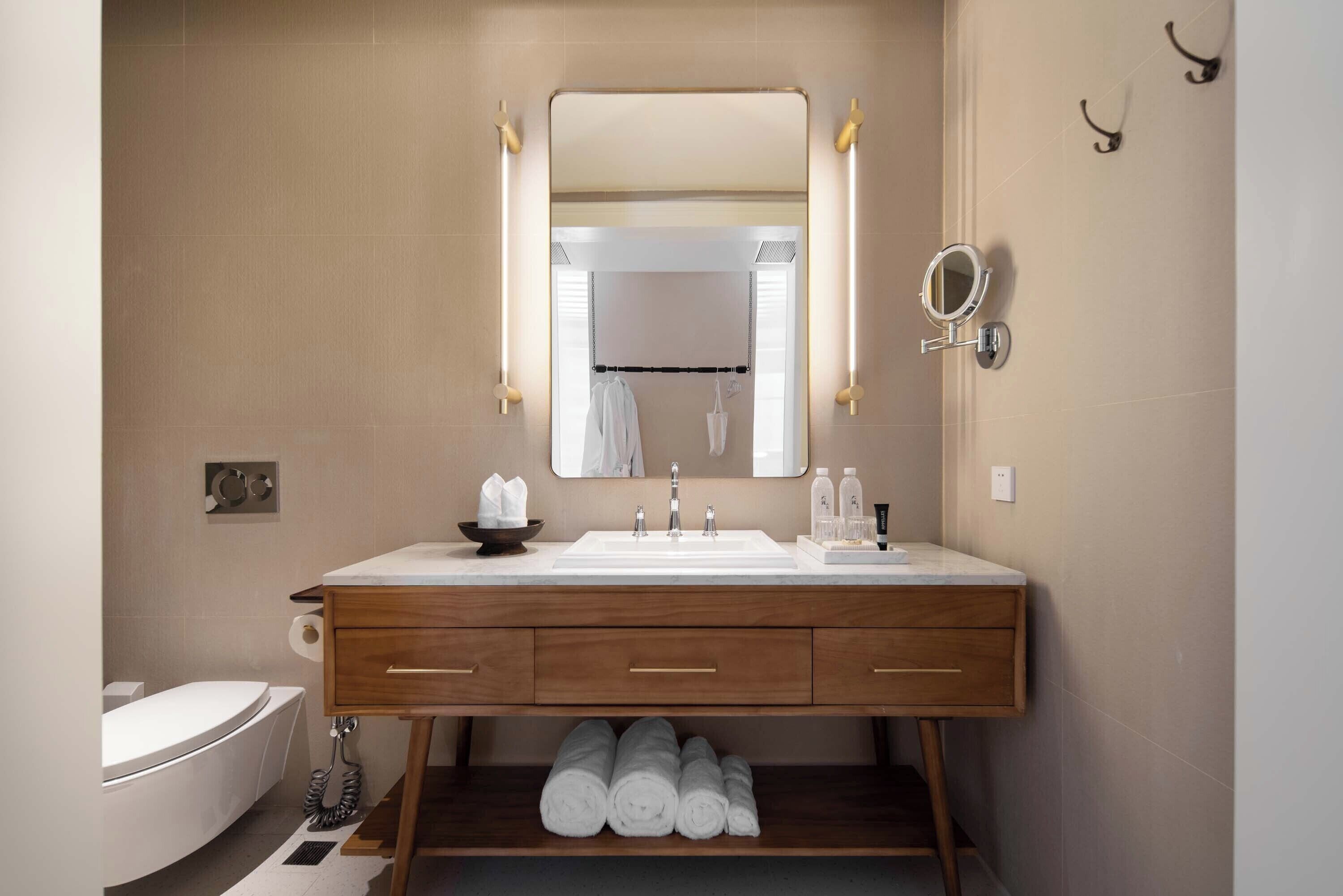 A modern bathroom with a large mirror, two sinks, wooden vanity, and a towel rack.