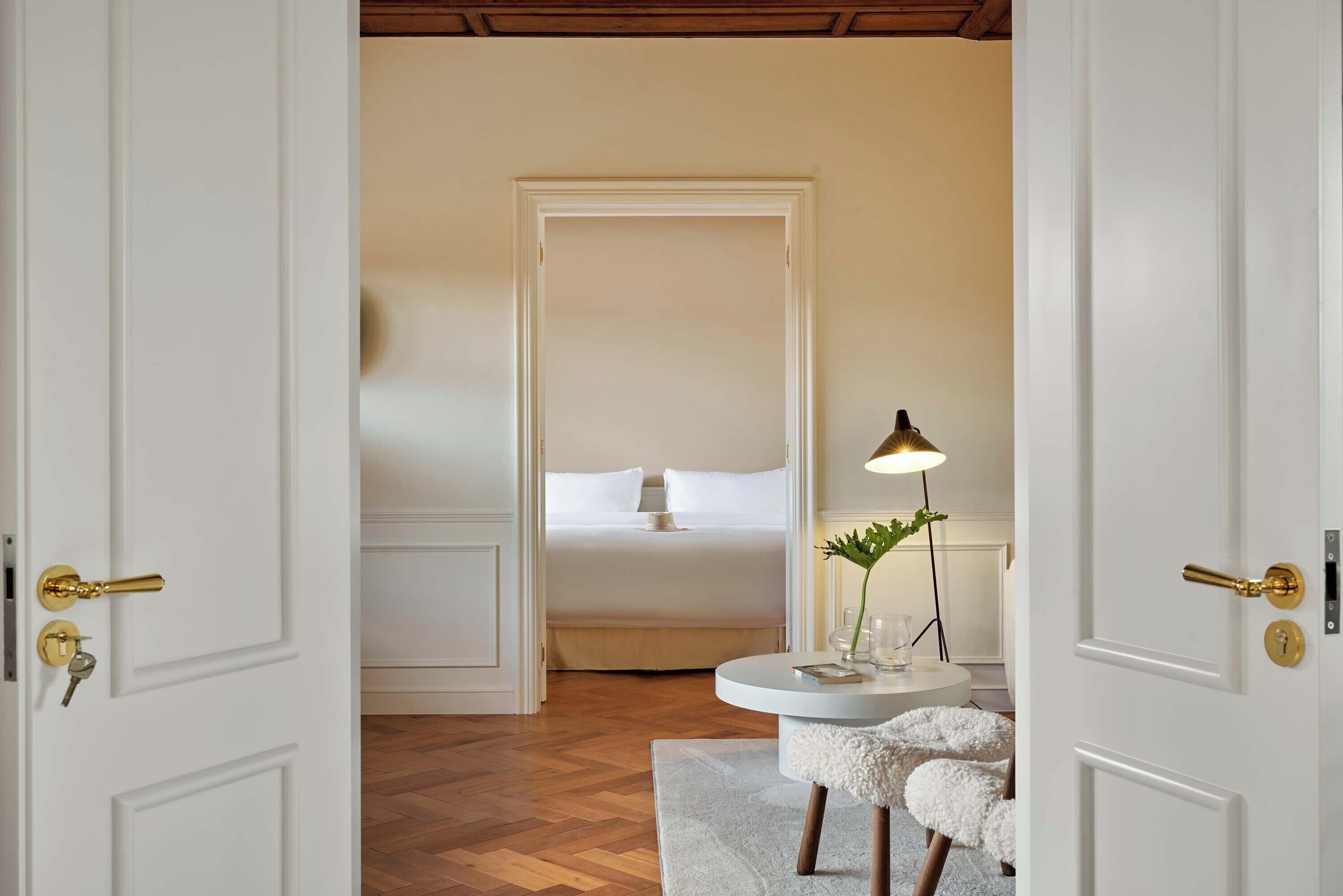 Een hotelkamer met een bed, een ronde tafel met een lamp en een zachte fauteuil.