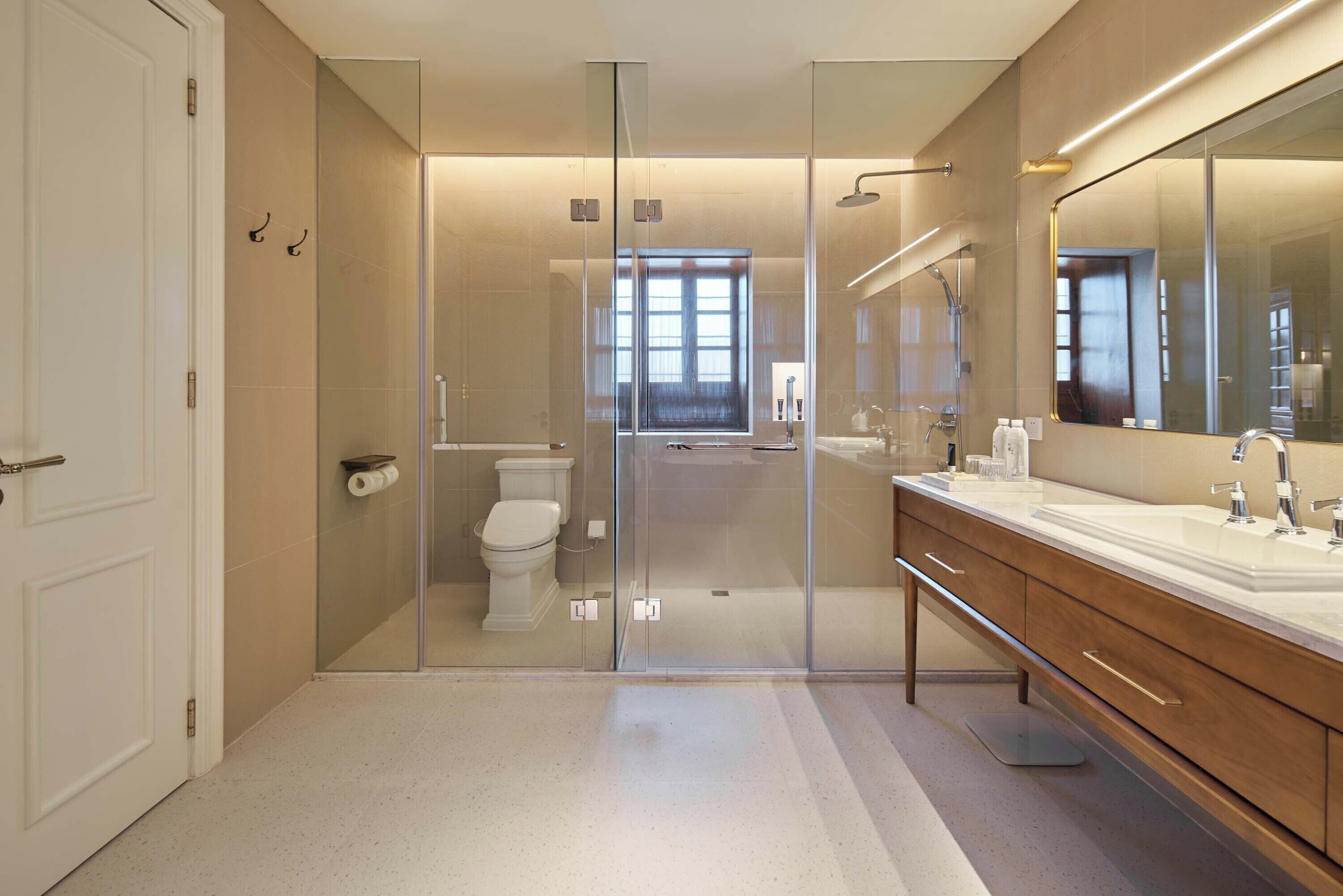 A modern bathroom with a glass shower enclosure, a toilet, and a vanity with a large mirror.