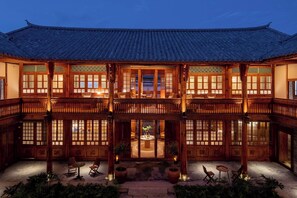 Un bâtiment de style coréen traditionnel, caractérisé par son architecture en bois, une cour intérieure et des espaces aménagés pour s’asseoir.