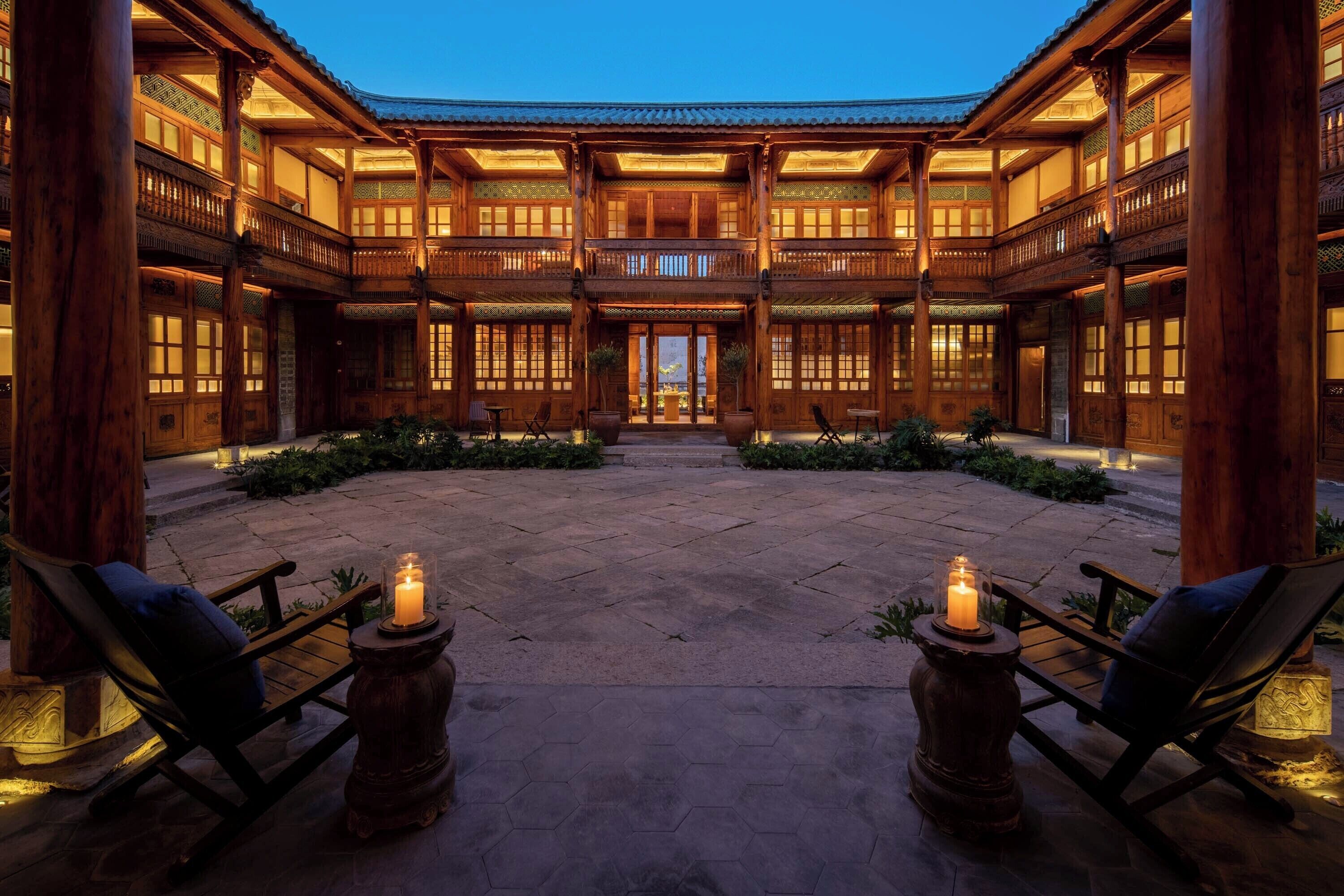 A traditional wooden building with a courtyard, featuring a central open space with seating and candles.
