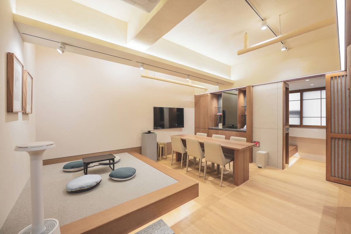 A modern, well-lit room with a wooden dining table, chairs, a bench, and a cat tree.
