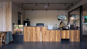 A modern reception area with a wooden reception desk, a digital screen, and a refrigerator stocked with beverages. - Wanluhu Xingyue Homestay (Heyuan)