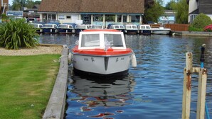 A narrow waterway with a boat docked at a wooden pier. - Wherry, pet friendly cottage. on the riverside with free fishing and mooring. (Wroxham)