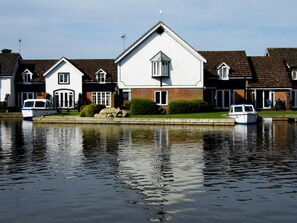 A row of houses by a calm water body with two boats docked.