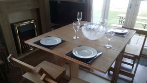 A dining area with a wooden table set for four, including plates, cutlery, and glasses. - Wherry, pet friendly cottage. on the riverside with free fishing and mooring. (Wroxham)