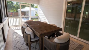 A covered patio with a wooden table and chairs, a view of the backyard, and a sliding glass door. - Minnesota Manor Home & Guest House-Your DeLand Getaway (DeLand)