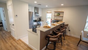 A modern kitchen with a central island, bar stools, and built-in appliances. - Minnesota Manor Home & Guest House-Your DeLand Getaway (DeLand)