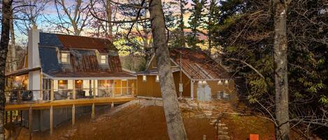 A rustic cabin with a large deck and a fire pit area.